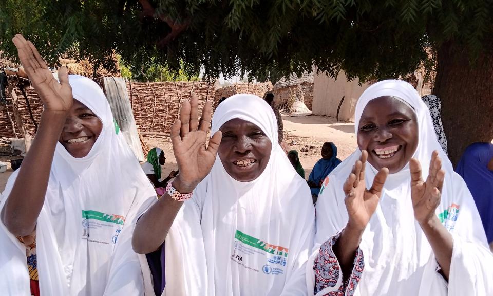 Three women smile and wave