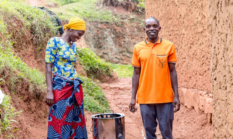 Emmanuel and Vestine standing side by side next to a fuel-efficient stove.  Photo: FAO Rwanda/ Christian Ngabonziza