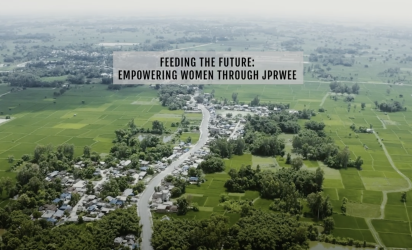 The image shows an aerial view of a rural landscape in Nepal, stretching far into the distance. There is an overlayed text that reads: "Feeding the Future: Empowering Women Through JPRWEE."